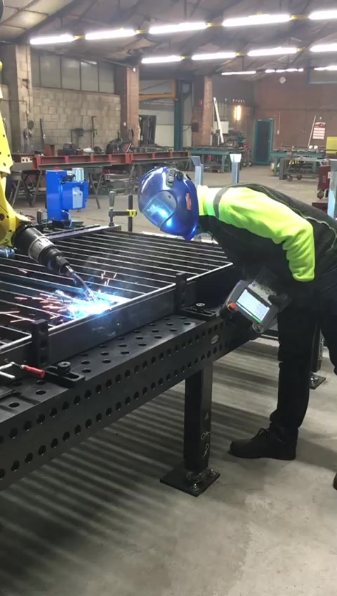 Lasser werkt naast de FANUC lasrobot in de werkplaats van Phoenix Steelworx